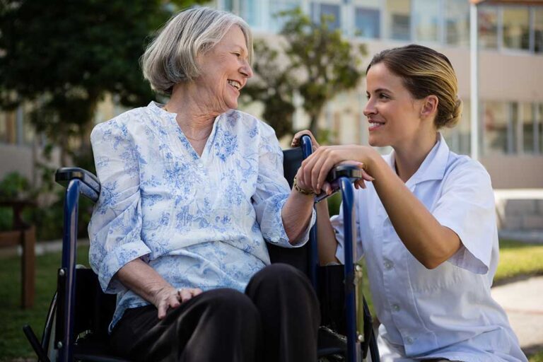 An adult daughter and her elderly mother sitting at a kitchen table having a thoughtful conversation.