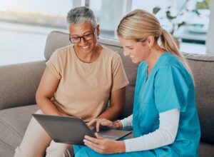 Older adult and family member reviewing Medicare paperwork at a kitchen table beside a calculator and folder.